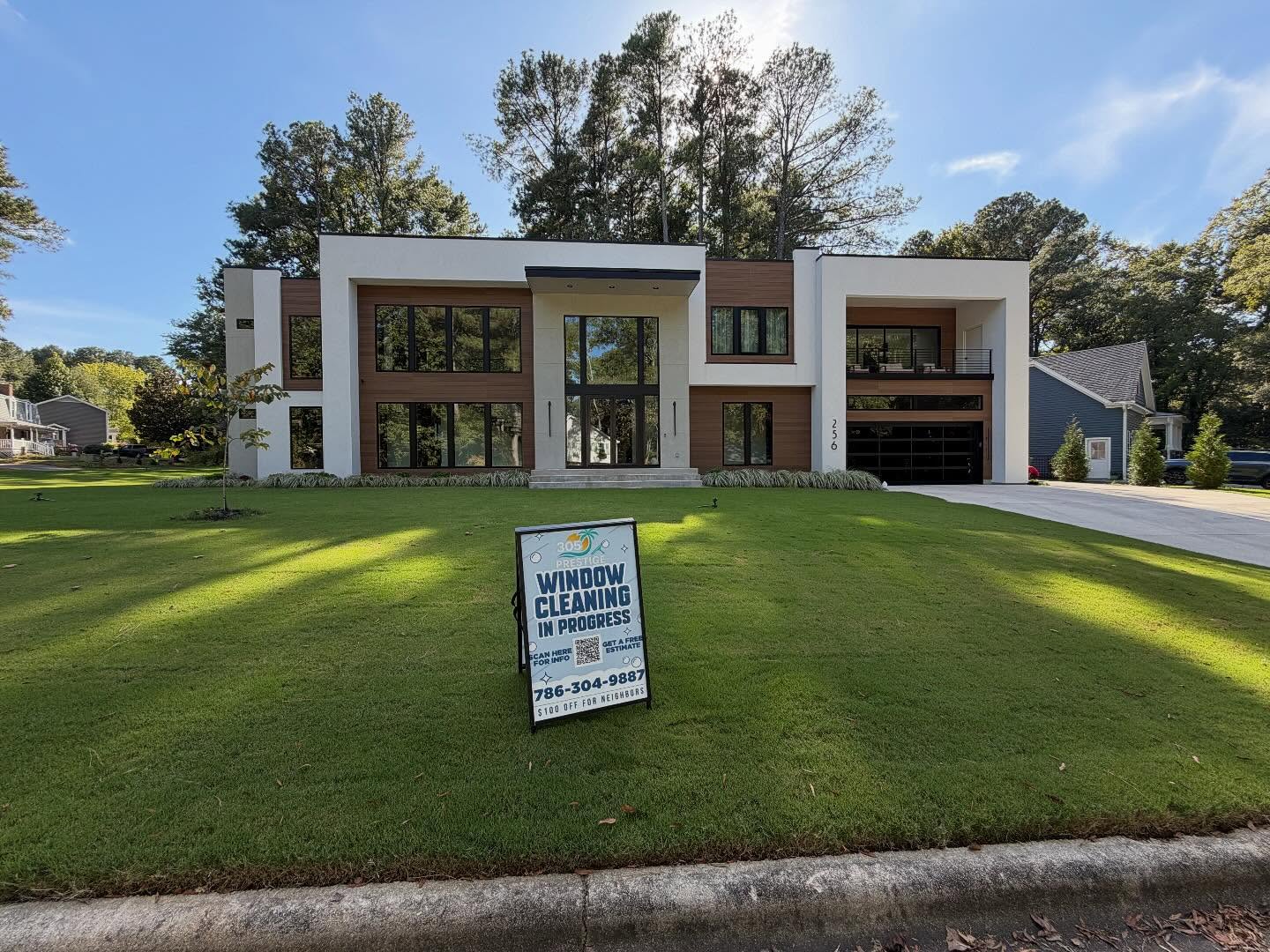 Modern luxury home with freshly cleaned glass and a service sign on the lawn